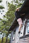 Man on ladder repairing roof