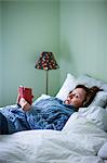 Woman in bed using cell phone