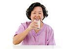 Portrait of happy Asian senior adult woman drinking a glass soy milk, isolated on white background.