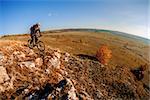 Wide angle view of a cyclist riding a bike on a nature trail in the mountains. people living a healthy lifestyle. Cyclist in the helmet and glasses. Fisheye. Landscape with hill, mound, horizon and blue sky.