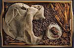 Linen bag with coffee grains, a hank of a cord, a stick of cinnamon, berry of a juniper and fruits of an anisetree on a wooden tray from a bamboo