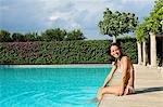 Young woman sitting by the swimming pool