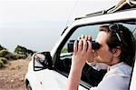 Man in car looking through binoculars