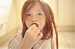 Girl eating strawberry on kitchen floor