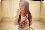 Girl eating strawberry on kitchen floor