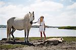 Girl petting horses on sandy beach