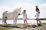 Girls with horses on sandy beach
