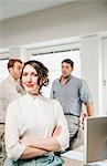 Portrait of female office worker, male colleagues in background