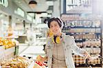 Portrait smiling, confident young woman with headphones grocery shopping in market