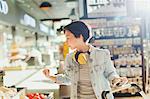 Young woman with headphones browsing, grocery shopping in market