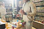 Young man grocery shopping, examining fruit in market