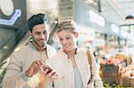 Smiling young couple using cell phone in grocery store market