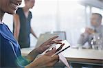 Close up smiling businesswoman using digital tablet in conference room meeting