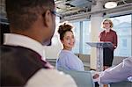 Smiling businesswomen turning and listening to businessman in conference audience