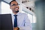 Smiling businessman working at laptop in office