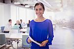 Portrait smiling businesswoman with paperwork in office