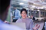 Businesswoman gesturing, talking at laptop in conference room meeting