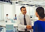 Businessman shaking hands with businesswoman in office