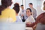 Smiling businesswoman talking to colleagues in conference audience