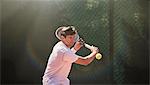 Young man playing tennis, swinging tennis racket