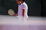Male tennis doubles talking on sunny tennis court