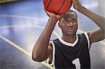 Focused young male basketball player shooting the ball on court