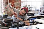 Male designer with tattoos assembling drone in workshop