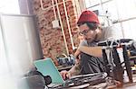 Male computer programmer working at laptop in workshop