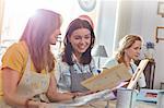 Smiling female artists painting picture frames in art class workshop