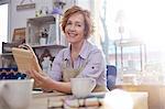 Portrait smiling mature female artist painting wood in art class workshop