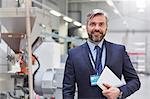 Portrait smiling, confident businessman with digital tablet in fiber optics factory