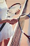 Tennis players handshaking in sportsmanship at net on sunny tennis court
