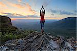 Arms outstretched,  reach for the sky. Stand on tippy toes, oh,oh,so high.  Woman on the edge of a mountain cliff with valley views stretches her arms toward the sky.