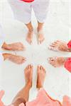 Top view image of feet of family standing on the white sand beach.