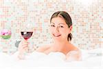 portrait of a happy girl in a bath with a glass of drink