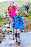 Happy hiking boy with trekking sticks in the mountains with his sister. Norway