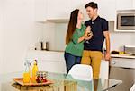 Young couple on the kitchen enjoying a  glass of white wine