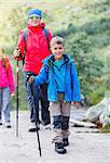 Happy hiking boy with trekking sticks in the mountains with his family. Norway