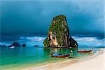 high rock in the sea, rain cloud and Thai boats near the shore