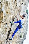 woman rock climber. rock climber climbs on a rocky wall. woman makes hard move