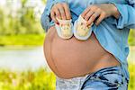 Belly of a pregnant woman close-up and booties in hands