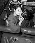 1940s CLOSE-UP COUPLE MAN WOMAN KISSING IN FRONT SEAT OF CONVERTIBLE CAR AT DRIVE-IN MOVIE