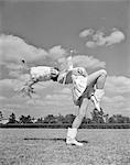 1940s 1950s TEENAGED GIRL MAJORETTE MARCHING ACROSS FIELD WITH BATON KICKING UP ONE LEG