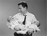 1960s  PANICKED MAN FATHER HOLDING CRYING TWIN BABIES
