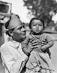 1930s PROUD NATIVE AMERICAN INDIAN NAVAJO MAN FATHER HOLDING BABY GIRL DAUGHTER LOOKING AT CAMERA