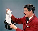 1960s 1970s MAN MAGICIAN WEARING RED SUIT PULLING WHITE RABBIT OUT OF TOP HAT