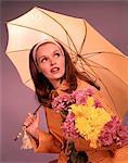1960s WOMAN HOLDING UMBRELLA AND YELLOW AND PINK FLOWERS LOOKING TOWARD SKY