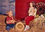 1960s LITTLE BOY AND GIRL BROTHER AND SISTER IN FARM SETTING HOLDING KITTENS