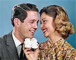 1960s SMILING COUPLE HEADS TOGETHER OVER PAIR BABY BOOTIES