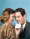 1960s SMILING COUPLE TOUCHING FOREHEADS LOOKING AT EACH OTHER HOLDING UP BABY SHOES